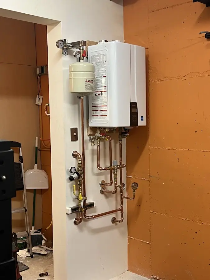 Plumbing technician inspecting water heater connections in Twin Lakes